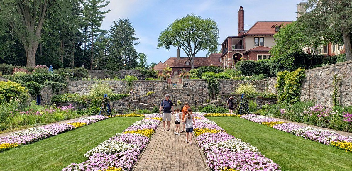 A family walks through a garden in front of a house.