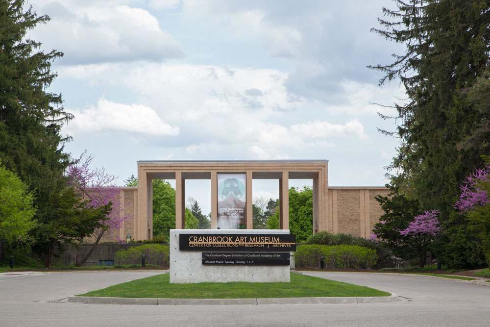 A sign in front of a building with trees in the background.