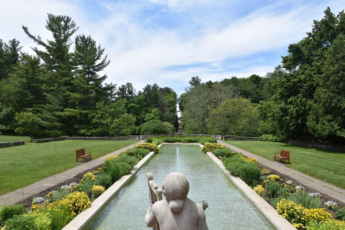 A statue sits in a fountain in the middle of a garden.