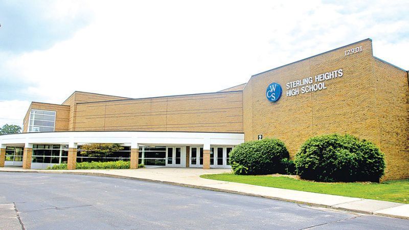 The front of a school building with a blue sign.